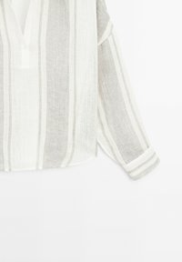 Chemise en lin à manches longues avec rayures verticales blanches et grises, poignets boutonnés et patte de boutonnage partielle à l'avant.
