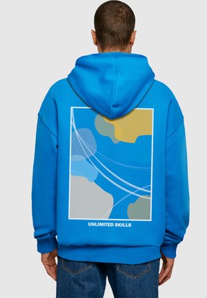 Blue hooded sweatshirt with a graphic design on the back, featuring abstract shapes in blue, yellow, and gray, and text reading “UNLIMITED SKILLS.”