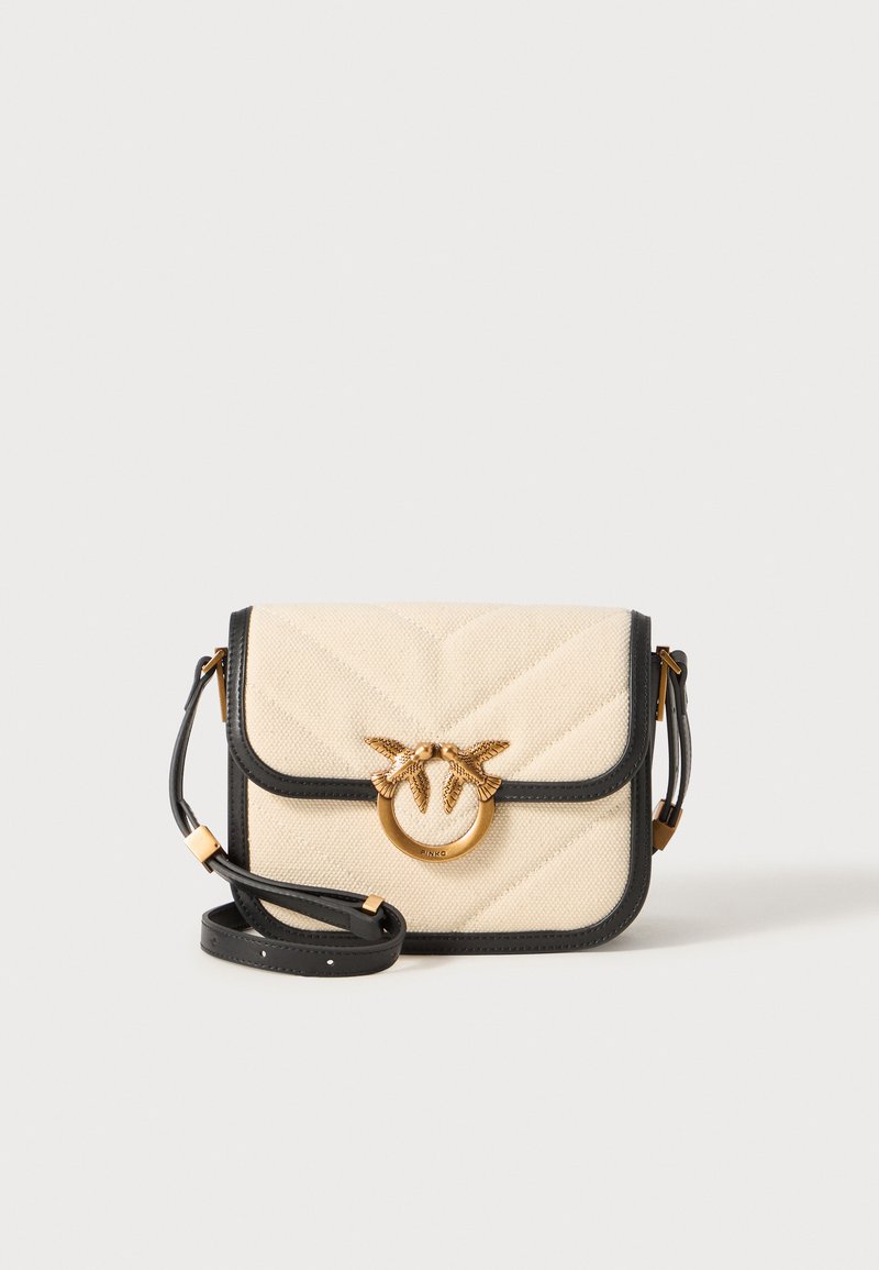 Bolsa crossbody de tecido bege com padrão em zigue-zague, detalhes em pele preta e um fecho circular dourado com dois desenhos de pássaros.