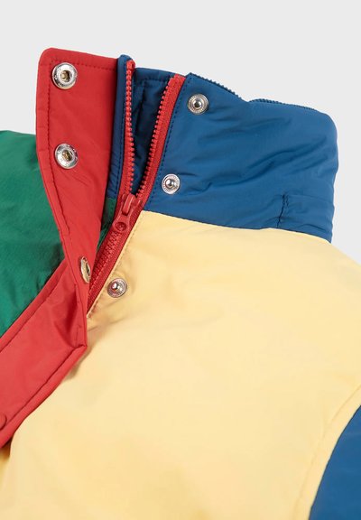 Colletto di una giacca a piumino colorata con pannelli rossi, verdi, gialli e blu. Include una zip rossa e bottoni a pressione in metallo per la chiusura.