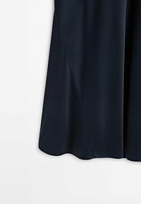 Vue en gros plan de la partie inférieure d'une jupe en tissu lisse bleu marine avec une couture diagonale subtile.