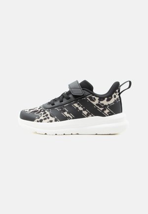 Pantof de sport alb-negru pentru copii, cu imprimeu leopard, dungi negre, curea cu Velcro și talpă albă groasă, prezentat din profil pe fundal alb.