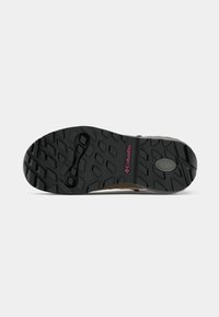 Semelle de chaussure noire en caoutchouc avec un motif de semelle texturé et un logo Columbia rose près du talon. Conçue pour la traction et la durabilité.