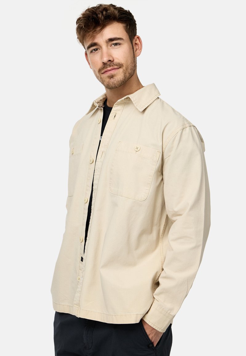 Beige bomulds skjorte med krave, knaplukning foran, to brystlommer og lange ærmer. Enkel design med en afslappet pasform og let tekstur.