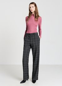 Gerippter pinker Langarm-Top kombiniert mit hochtaillierten, locker sitzenden schwarzen und grauen karrierten Hosen, abgerundet mit spitzen schwarzen Absätzen.