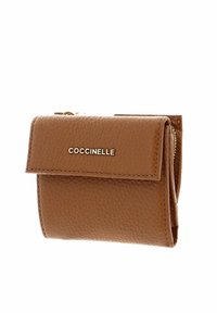 Portefeuille en cuir marron texturé avec fermeture à rabat et logo "COCCINELLE" doré sur le devant.