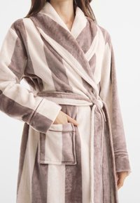 Pasiasty, miękki szlafrok w jasnoróżowym i taupe, z kołnierzem szalowym, paskiem w talii, przednią kieszenią i puszystą teksturą.