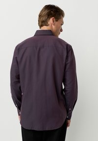 Dunkellila langärmliges Hemd mit Standardkragen. Verfügt über geknöpfte Manschetten und einen geschwungenen Saum. Hergestellt aus glattem, strukturiertem Stoff.