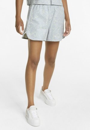 Shorts bleu clair avec un motif floral subtil, dotés d'une taille élastique et d'une coupe décontractée, associés à des baskets blanches.