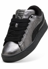 Metallisch graue Sneaker mit einer strukturierten schwarzen Sohle, dicken schwarzen Schnürsenkeln und einem gepolsterten Knöchelkragen. Mit Puma-Logo auf der Zunge.