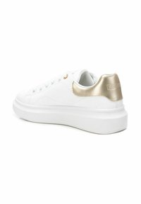 White sneakers with a smooth leather upper, gold metallic accents on the heel, and a thick white rubber sole. Features lacing with metal eyelets.