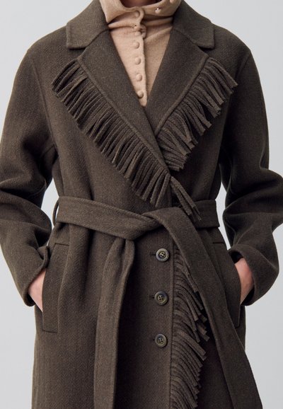 Cappotto in lana marrone con design a frange, vita con cintura, ampio colletto e chiusura con bottoni. Tessuto testurizzato con tasche laterali.
