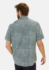 Korte mouw shirt met een kruispatroon in marineblauw en wit, gemaakt van lichtgewicht stof. Voorzien van een puntige kraag en knoopdetails.
