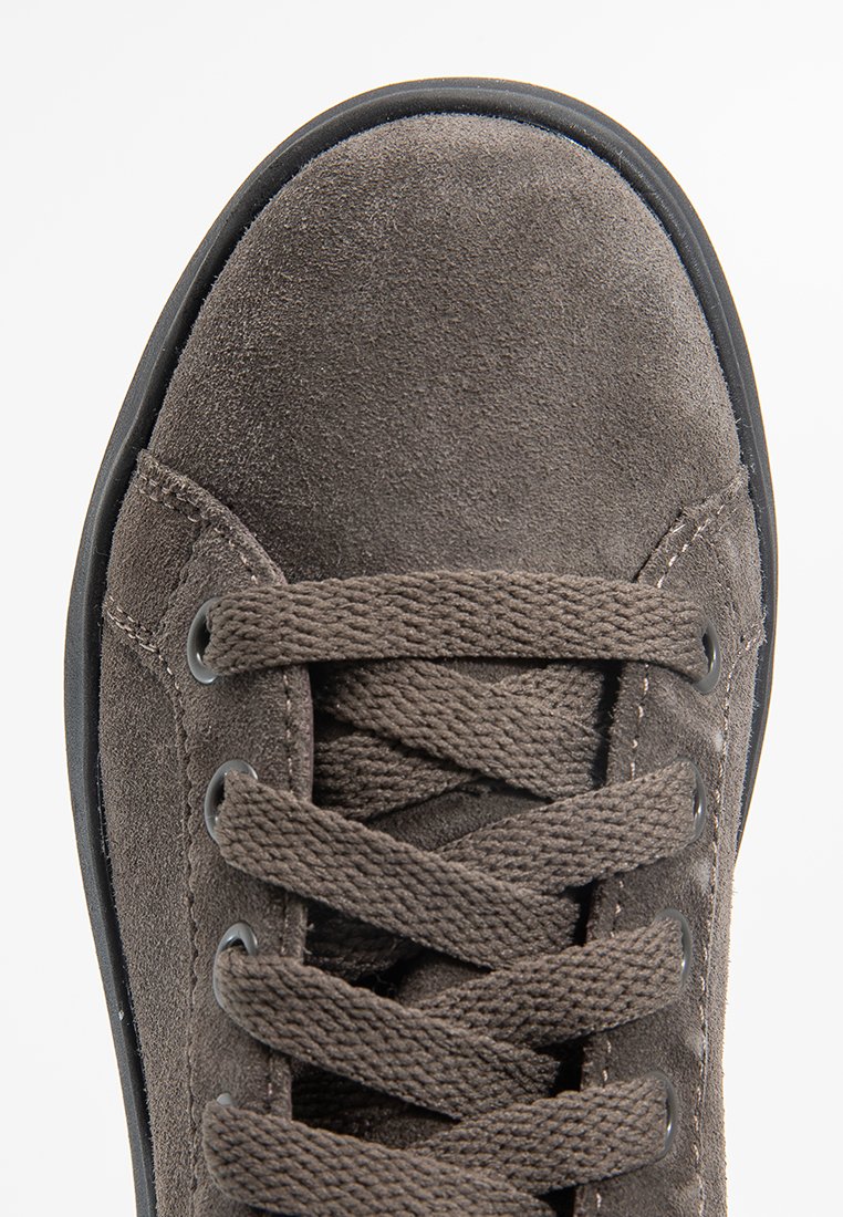 Braune Wildledersneaker von oben, mit abgerundeter Form, flachen Schnürsenkeln, runden Ösen, strukturiertem Obermaterial und einer schwarzen Gummisohle.