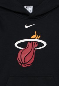 Crna dukserica s velikim crveno-žutim logotipom Miami Heata, s bijelim kolom i grafikom košarkaške lopte, izrađena od pamučnog materijala.