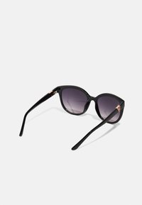 Black cat-eye sunglasses with gradient purple lenses, high-shine plastic frame, and gold-tone accents on the temples.
