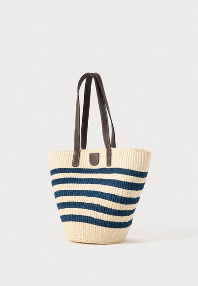 Sac cabas beige tissé avec des rayures horizontales bleu marine et des poignées et finitions en cuir marron foncé.