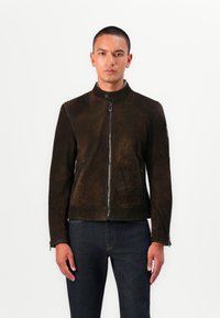 Jachetă din suede maro cu guler stand, închidere frontala cu fermoar și buzunare laterale; prezintă un material texturat și un design ajustat.