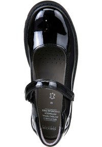 Scarpa in vernice nera con punta arrotondata, suola piatta e una fascia sopra per una chiusura sicura. Nota per il suo caratteristico motivo di perforazione nella soletta.