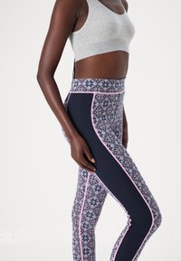Leggings med ett vintermönster i marinblått, med rosa accenter och en texturerad midja. Kombineras med en grå kort topp.