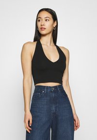 Top cropped preto com decote V profundo, combinado com jeans de ganga escuros de cintura alta. Tecido suave e design ajustado.