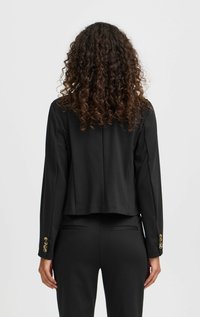 Schwarze kurze Blazerjacke aus gewobenem Stoff. Verfügt über lange Ärmel und goldene Knopfdetails an den Bündchen. Taillierte Passform mit glatter Textur.