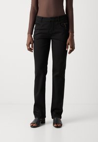 Zwarte skinny jeans met voorkruimelzakken en ritsaccenten. Gekocht met zwarte open-toed hakken, voorzien van een gladde stofstructuur.