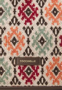 Knit fabric handbag featuring intricate multi-colored patterns in red, orange, green, and black, with a brown leather logo accent.