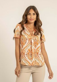 Blouse à manches courtes en tissu léger avec un motif cachemire orange et crème. Encolure en V et détail à nouer à l'avant.