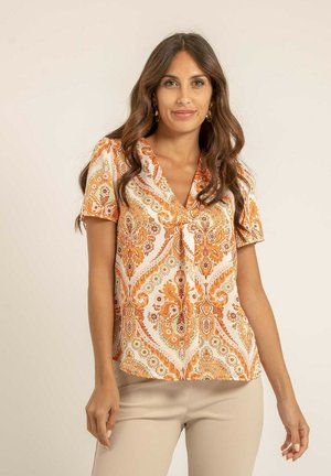 Blouse à manches courtes en tissu léger avec un motif cachemire orange et crème. Encolure en V et détail à nouer à l'avant.