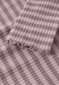 Gestreifter Strickstoff in Lila und Hellrosa mit gerippter Textur; verfügt über berschnittene Kanten. Die Streifen variieren in der Breite.