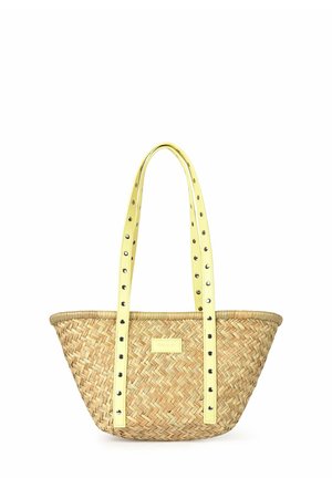 Sac cabas en paille tressée avec de longues anses jaunes décorées d'œillets métalliques et une petite étiquette rectangulaire sur le devant.