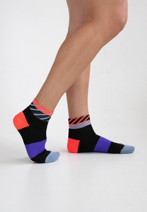 Bunte Knöchelsocken in Schwarz, Neonorange, Lila und Grau mit einem geometrischen Muster und kontrastierenden Blockabschnitten. Atmungsaktiver Stoff.