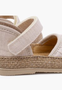 Sandali in tessuto beige con chiusura in Velcro, suola intermedia decorativa in juta intrecciata e suola in gomma texturizzata. Design aperto per la traspirabilità.