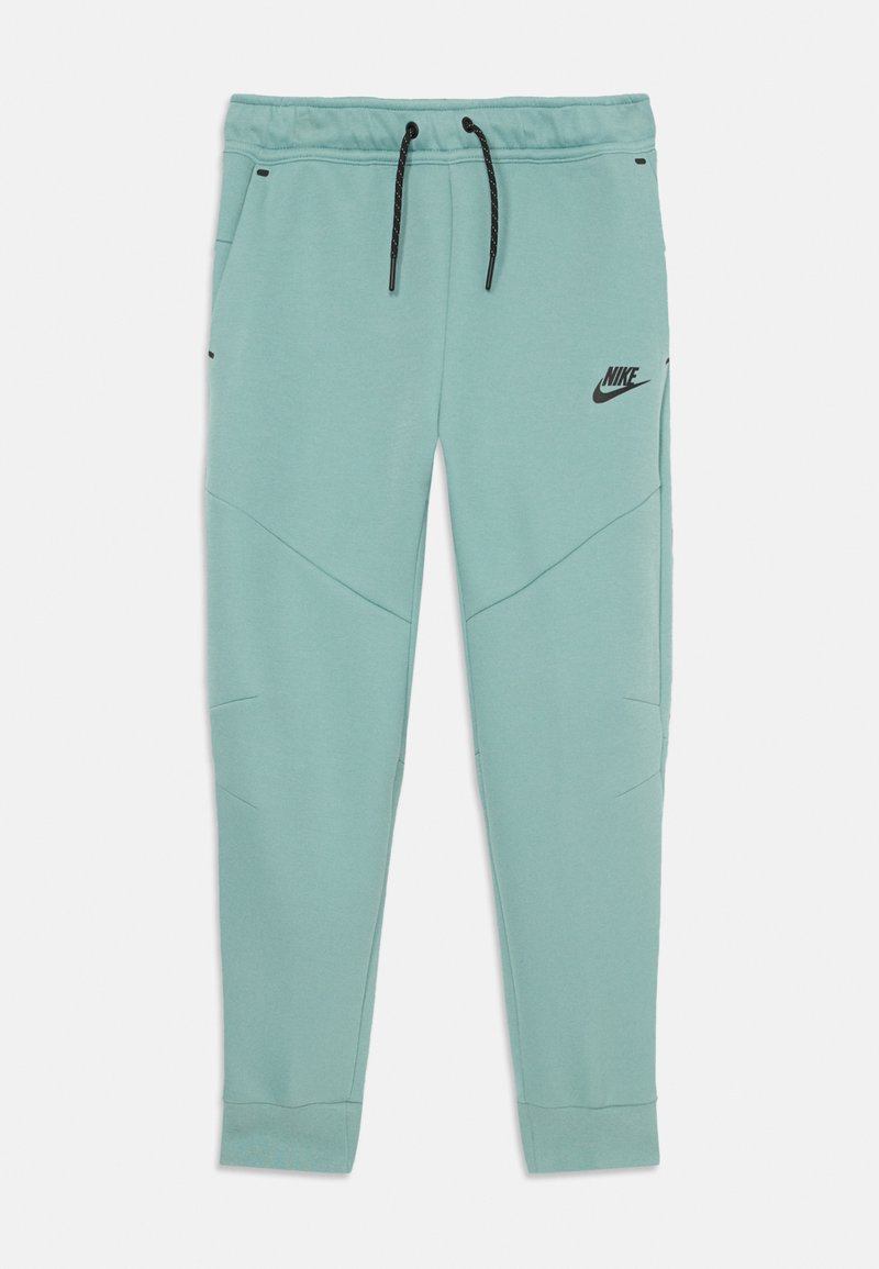 Gaišs teksta pelēkais bikses, kas izgatavotas no mīksta materiāla. Iezīmē melnu Nike logotipu, auklas jostu un ģeometriskus paneļu detaļas.