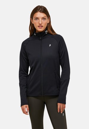 Zwarte ritsjack gemaakt van een zachte, rekbare stof met een hoge kraag, voorzien van zijzakken en een logo op de borst.