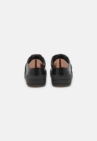 Black sneakers with a glossy brown accent on the heel, featuring a textured design, rubber sole, and a smooth upper material.