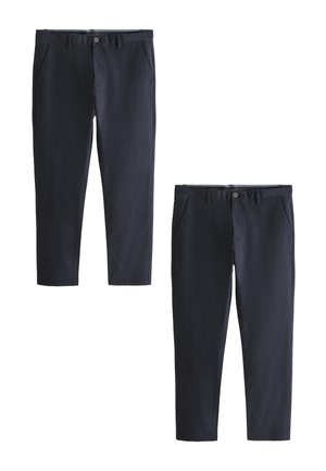 Dwie pary granatowych, dopasowanych spodni z przednimi kieszeniami i zapinanymi na guziki pasami, prezentowane na białym tle.