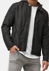 Mustavi nahka takki, jossa on vetoketju, harmaa hupparivuori, tikkaukset olkapäissä ja sivutaskut; takissa on kapea muotoilu.