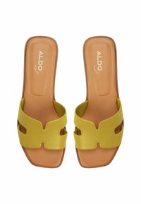 Žluté skluzné sandály se širokým, vyřezávaným designem pásku. Hladký syntetický materiál s hnědou podrážkou a embosovaným logem. Plochý a otevřený tvar.