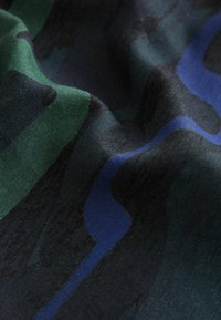 Tessuto a fantasia in verde, blu e nero. Texture liscia con elementi di design ondulati. Una leggera lucentezza crea profondità nei colori e nei motivi.