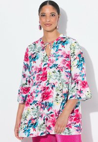 Blumenbluse mit weißem Hintergrund und pinken, blauen und gelben Mustern, Schlüssel-Ausschnitt und gerafften Dreiviertelärmeln.