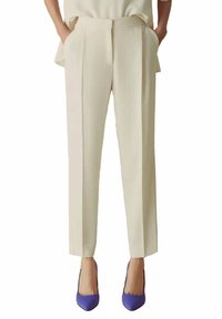 Pantaloni formali color crema con vestibilità su misura, caratterizzati da frontale piatto, tasche laterali e una texture liscia. Abbinati a tacchi viola.
