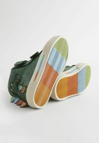 Grüne Leder-Sneaker mit Klettverschlüssen, die ein verspieltes Krokodil-Design zeigen. Die Sohlen haben ein mehrfarbiges Fischgrätenmuster.