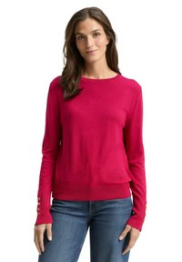 Sweter w kolorze fuksji wykonany z miękkiej dzianiny, z okrągłym dekoltem i długimi rękawami ozdobionymi złotymi guzikami na mankietach.