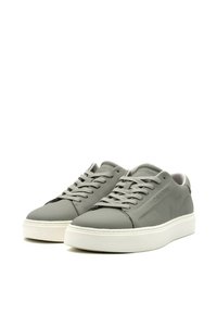 Sneakers in pelle grigia con una texture liscia, suola in gomma bianca e lacci piatti. Presentano un logo discreto sul lato e un design minimalista.