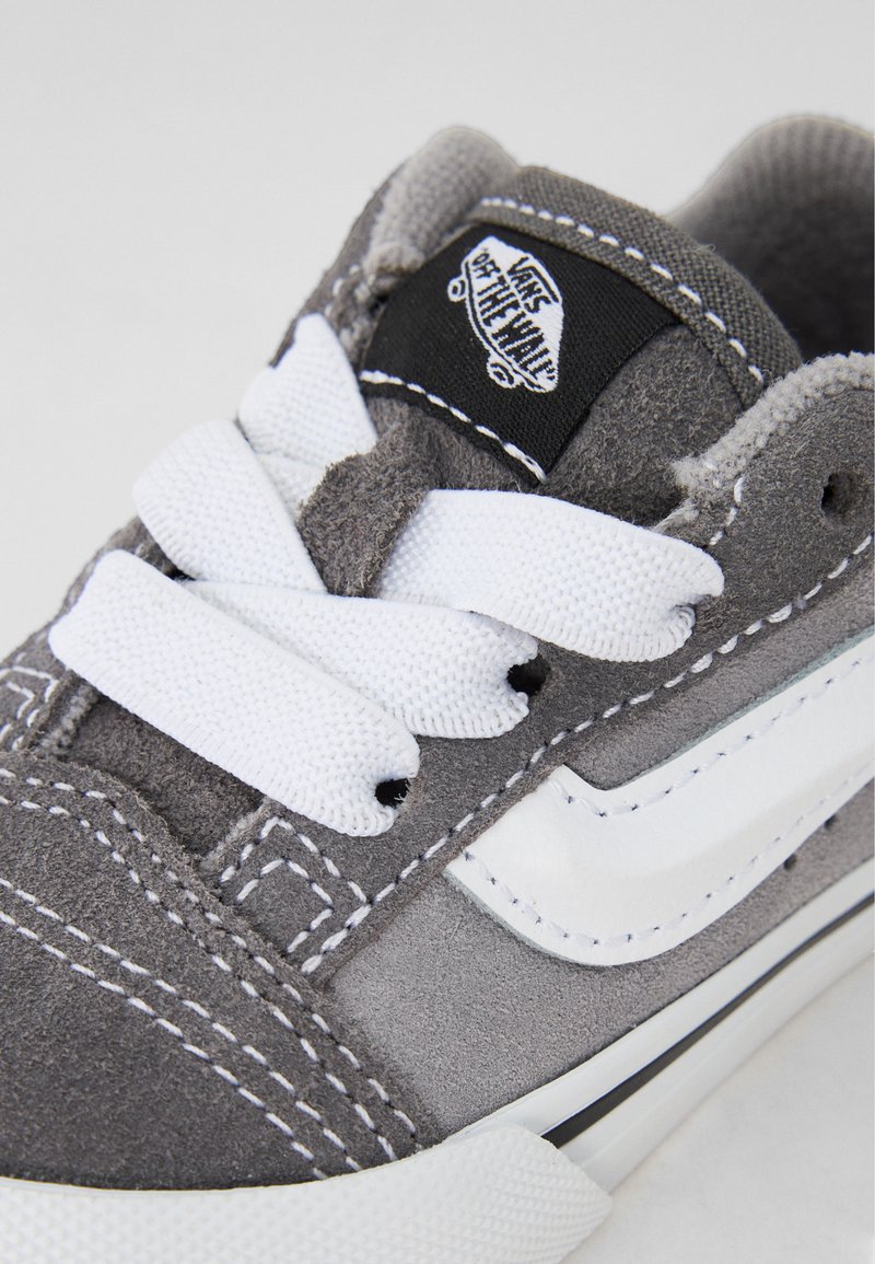 Baskets en daim gris avec des lacets blancs, dotées d'une étiquette de logo Vans noire et d'un accent en cuir blanc. Détails cousus en fil blanc contrastant.