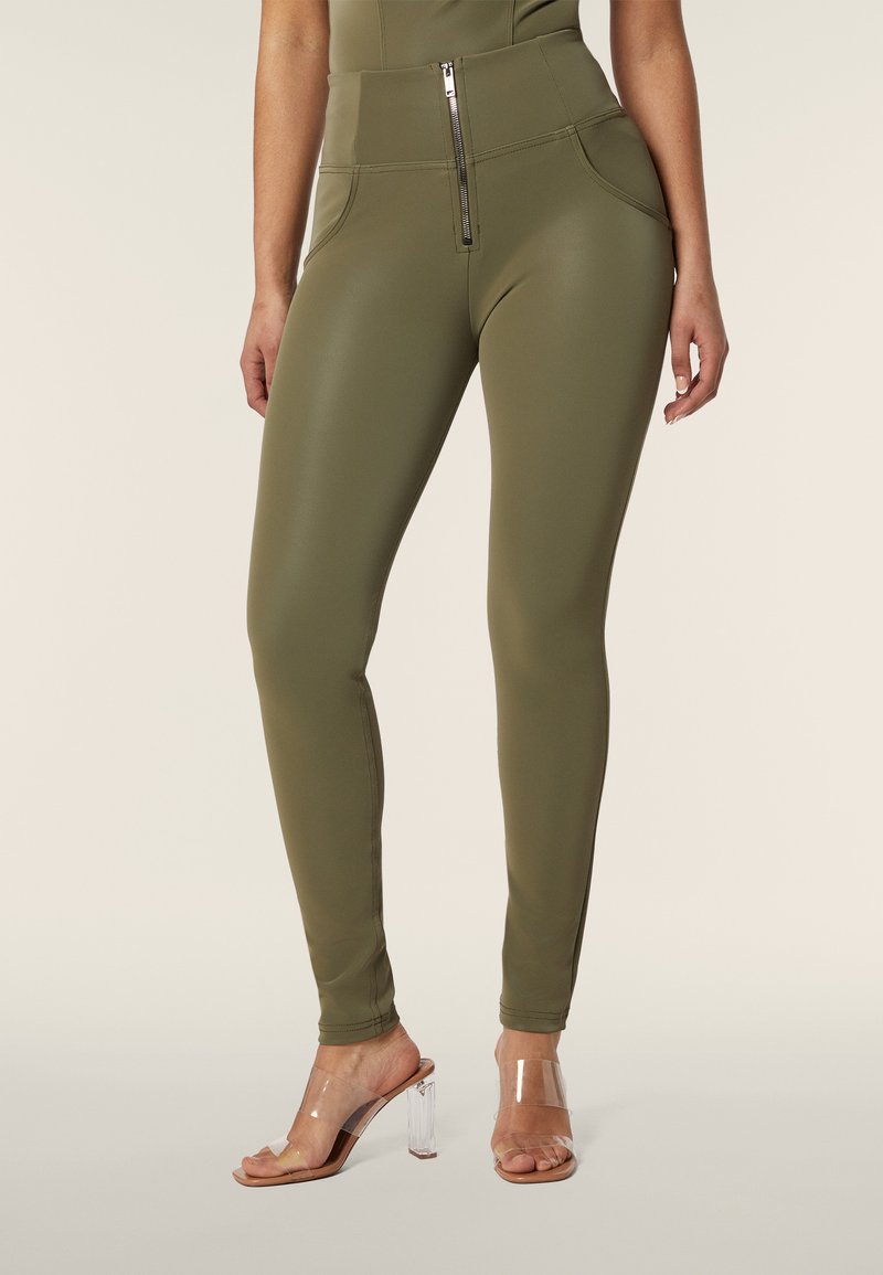 Leggings verde oliva con vita alta, dotati di una cerniera frontale e due tasche laterali. Realizzati in un materiale morbido e elasticizzato.