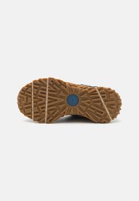 Brown rubber outsole with a textured design featuring grooves and ridges. Reinforced edge and a blue circular accent at the center.