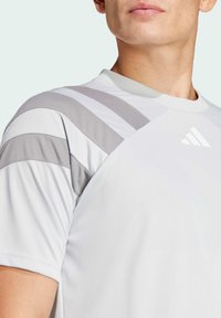Witte sportieve T-shirt met grijze gestreepte accenten op de schouders. Glad stof, ronde hals ontwerp en klein logo op de borst.
